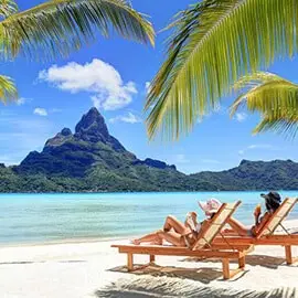 Private boat on a shallow reef with palm-framed view