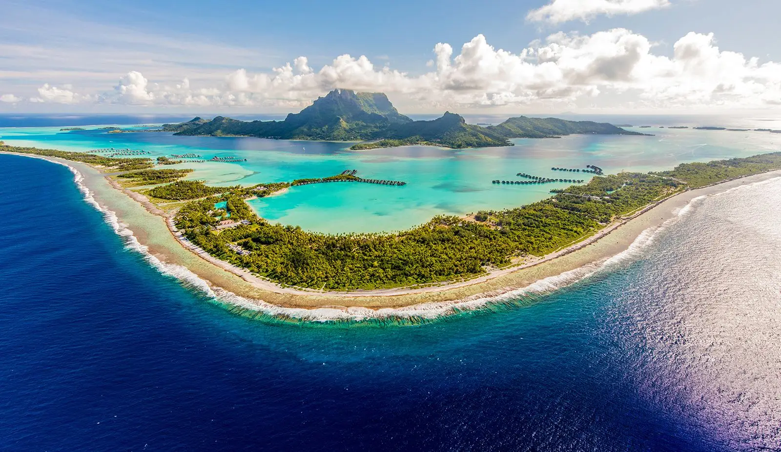 Panoramic lagoon and mountain ridge beyond overwater villas