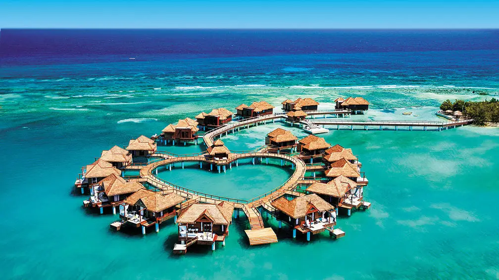 Wide view of overwater villas under blue skies